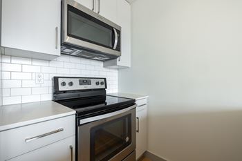 A modern kitchen with a black stove and white cabinets.